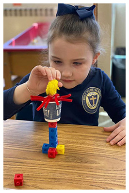 Student stacking blocks and other objects